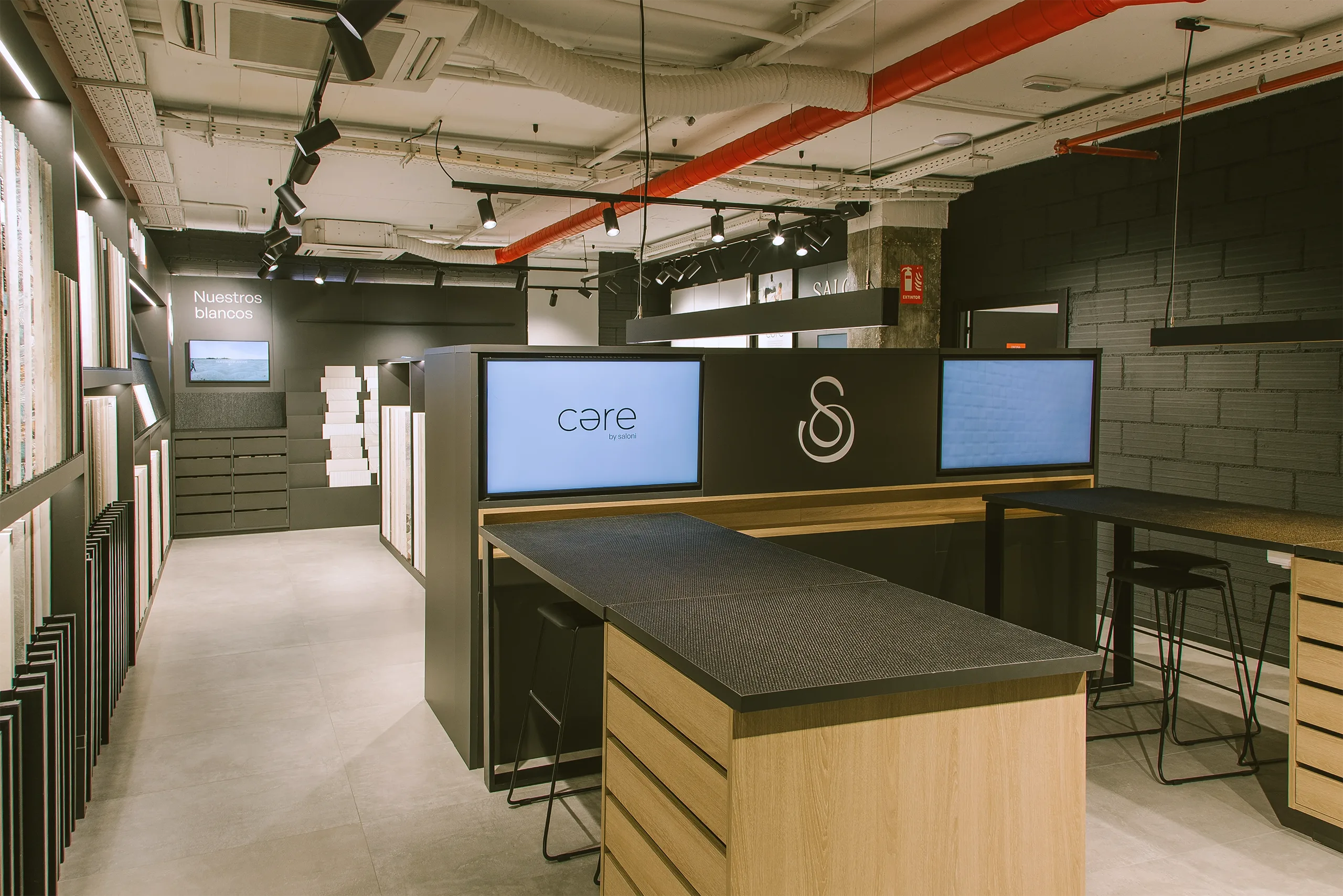 Espacio Care by Saloni en showroom Madrid con pantallas digitales, mobiliario a medida y zona de muestrario de blancos