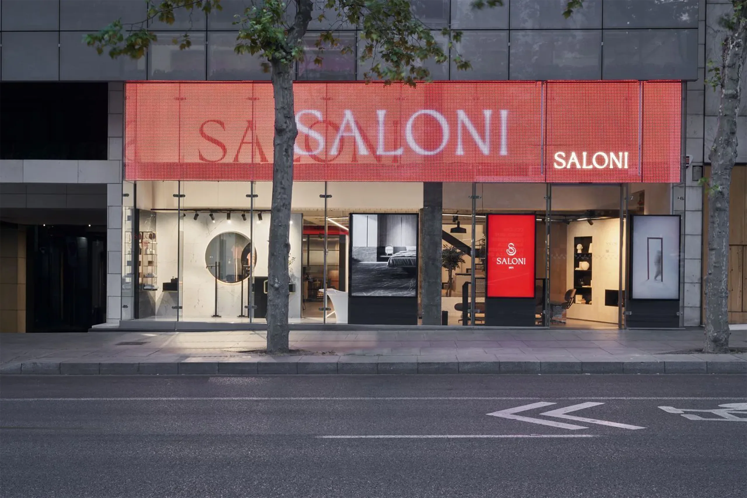 Fachada del showroom SALONI Madrid con pantalla LED roja a doble altura y escaparate iluminado de cerámica