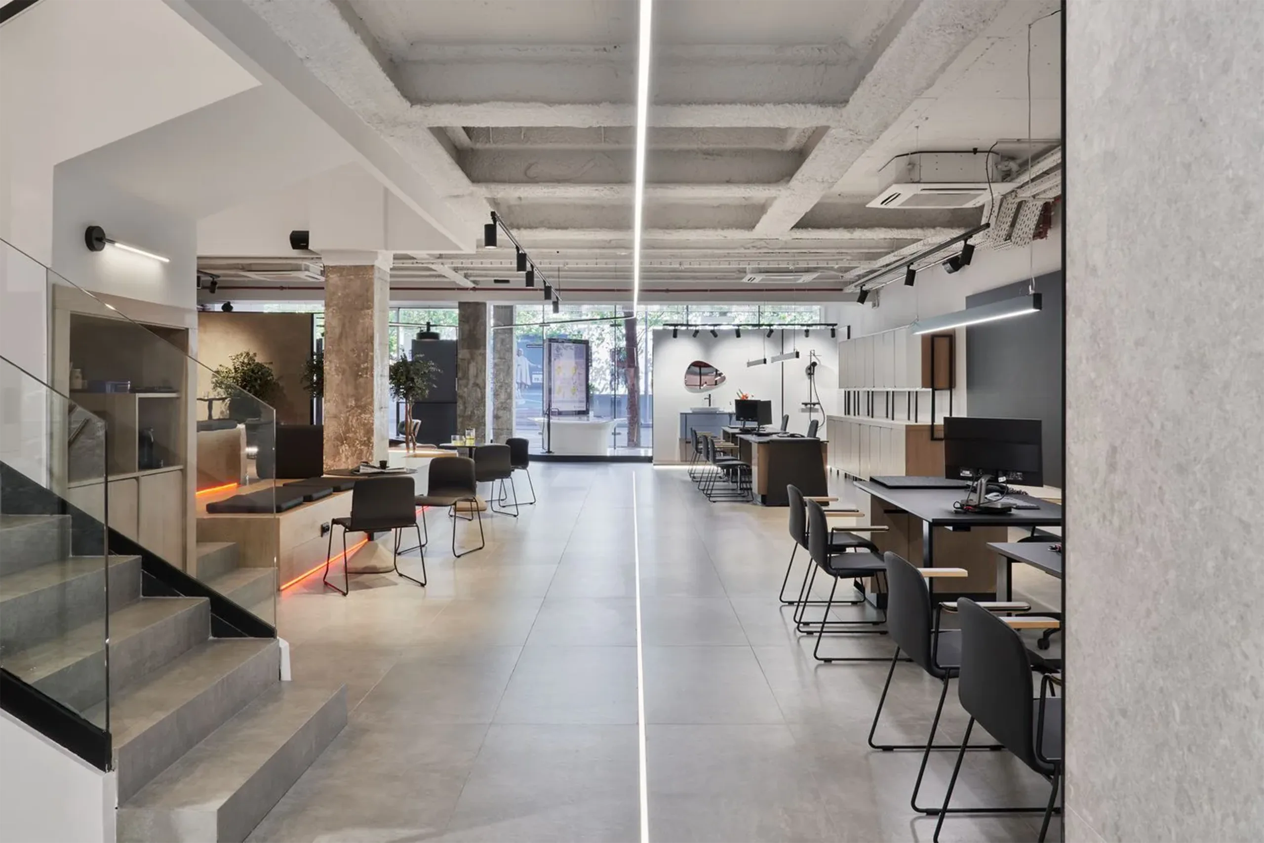 Vista general del interior del showroom SALONI Madrid con techo industrial visto, iluminación lineal y zonas de trabajo diseñadas por huuun