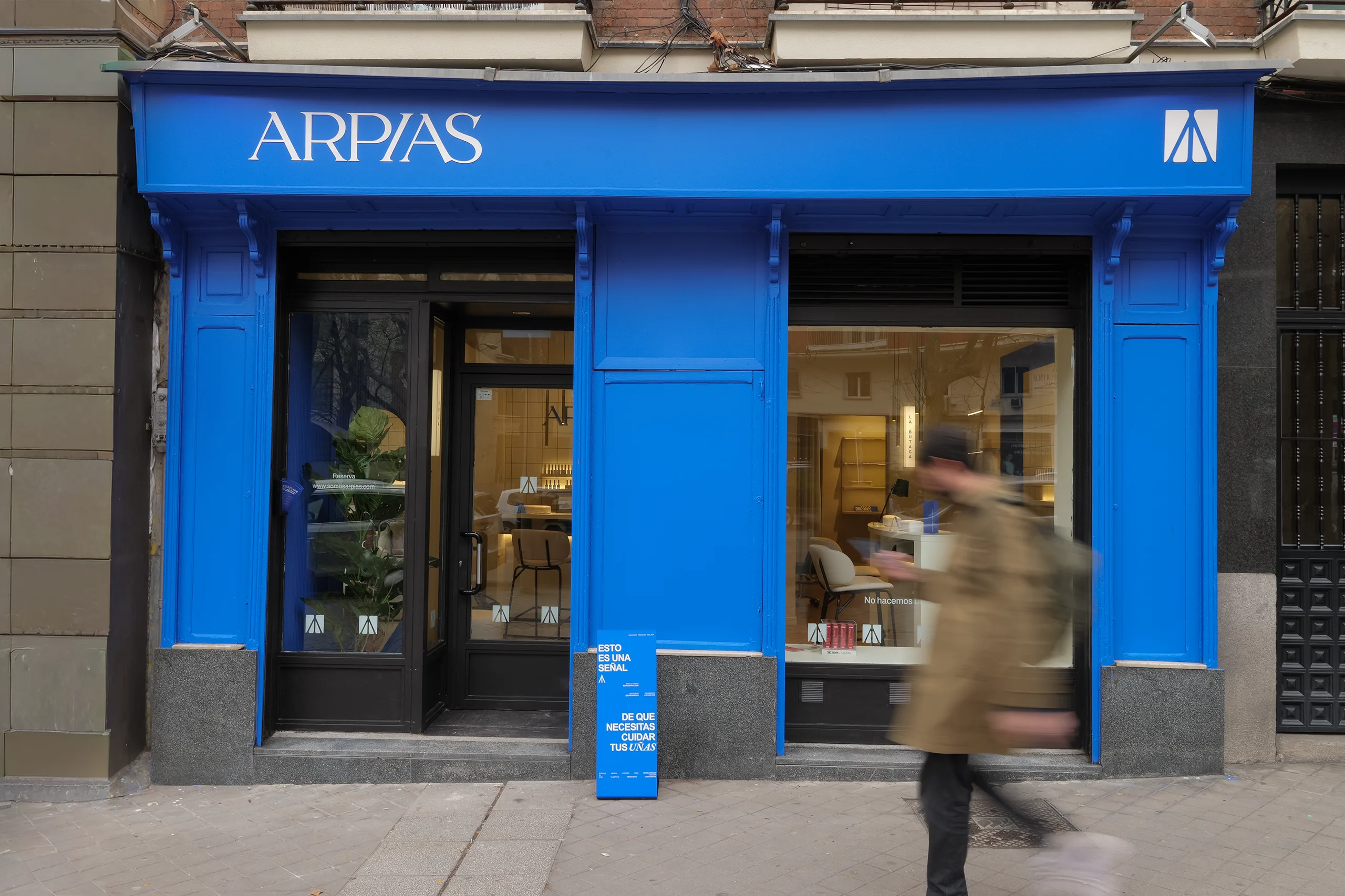Fachada de Arpías en la calle Atocha (Centro, Madrid) con frente azul intenso completo, rótulo ARPÍAS, escaparate doble con vista al interior y edificio histórico madrileño