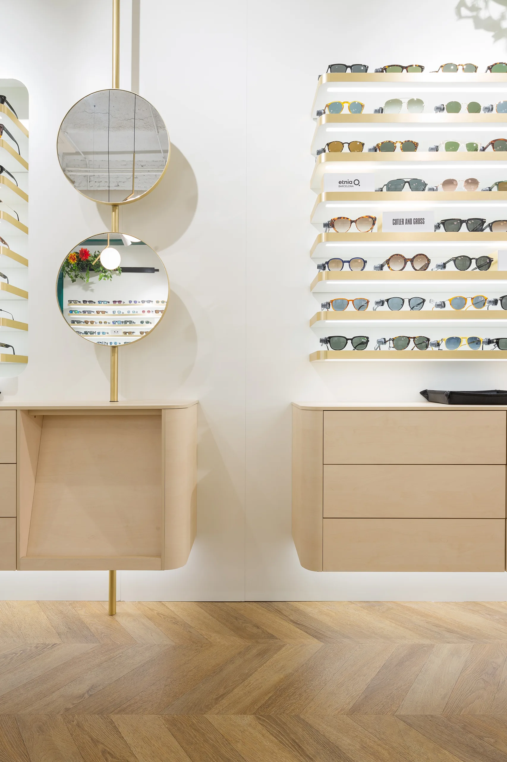 Expositor Cottet de gafas de sol con baldas retroiluminadas de latón, espejos circulares y mueble de abedul