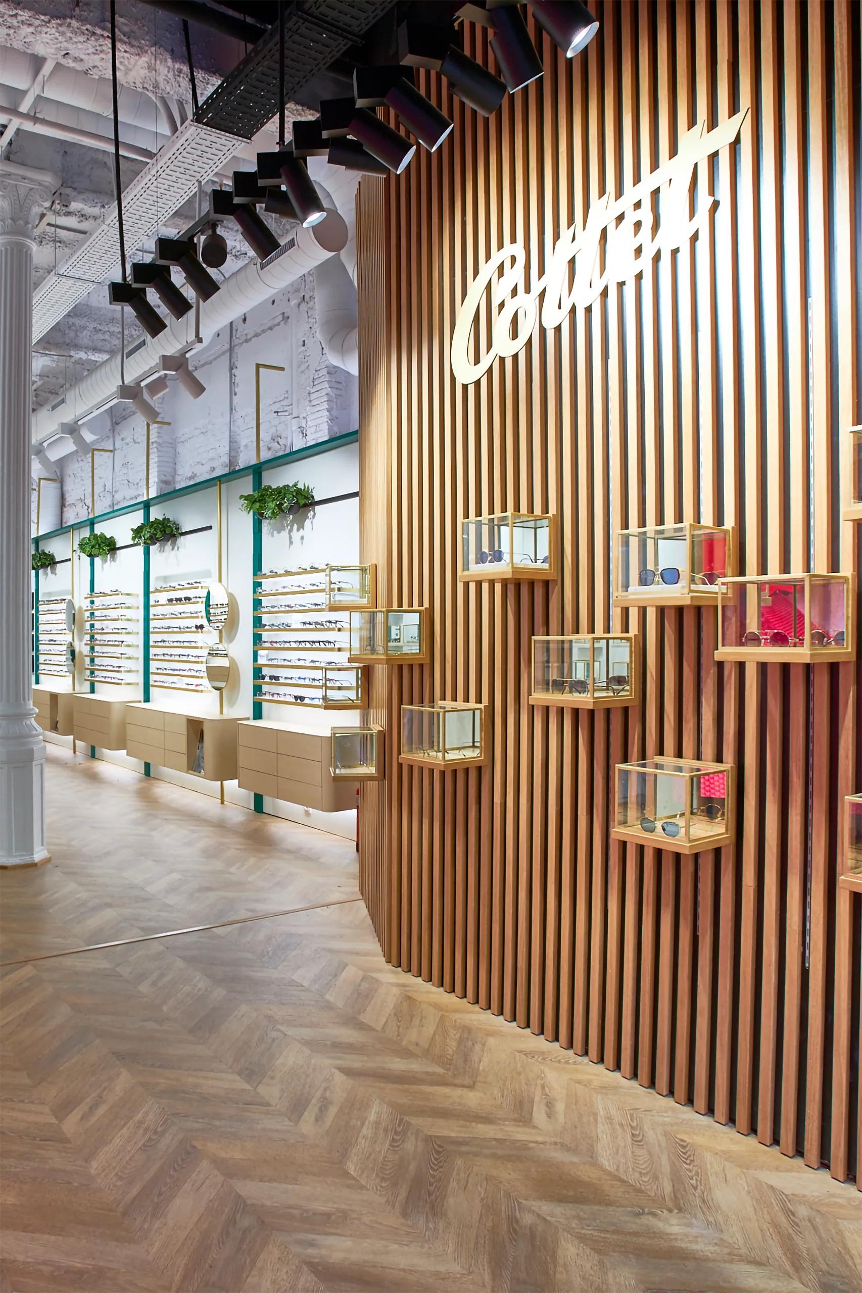 Muro de lamas de madera en Cottet Barcelona con logotipo retroiluminado y vitrinas cúbicas de latón