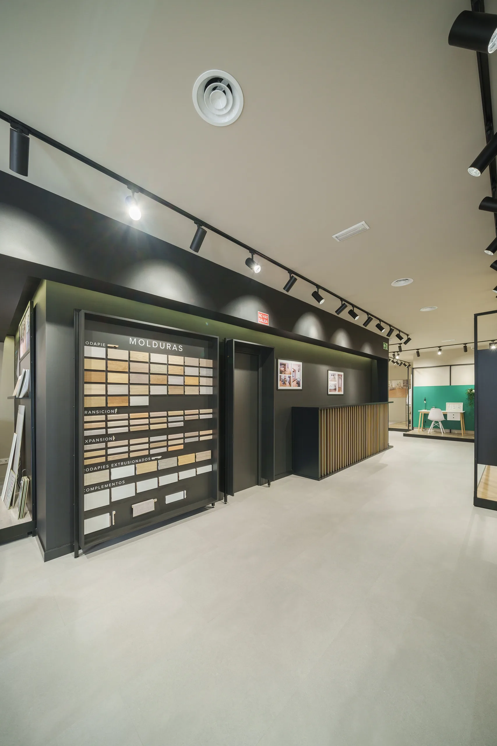 Expositor de molduras y rodapiés FAUS sobre pared negra con iluminación de carril en la tienda de Madrid