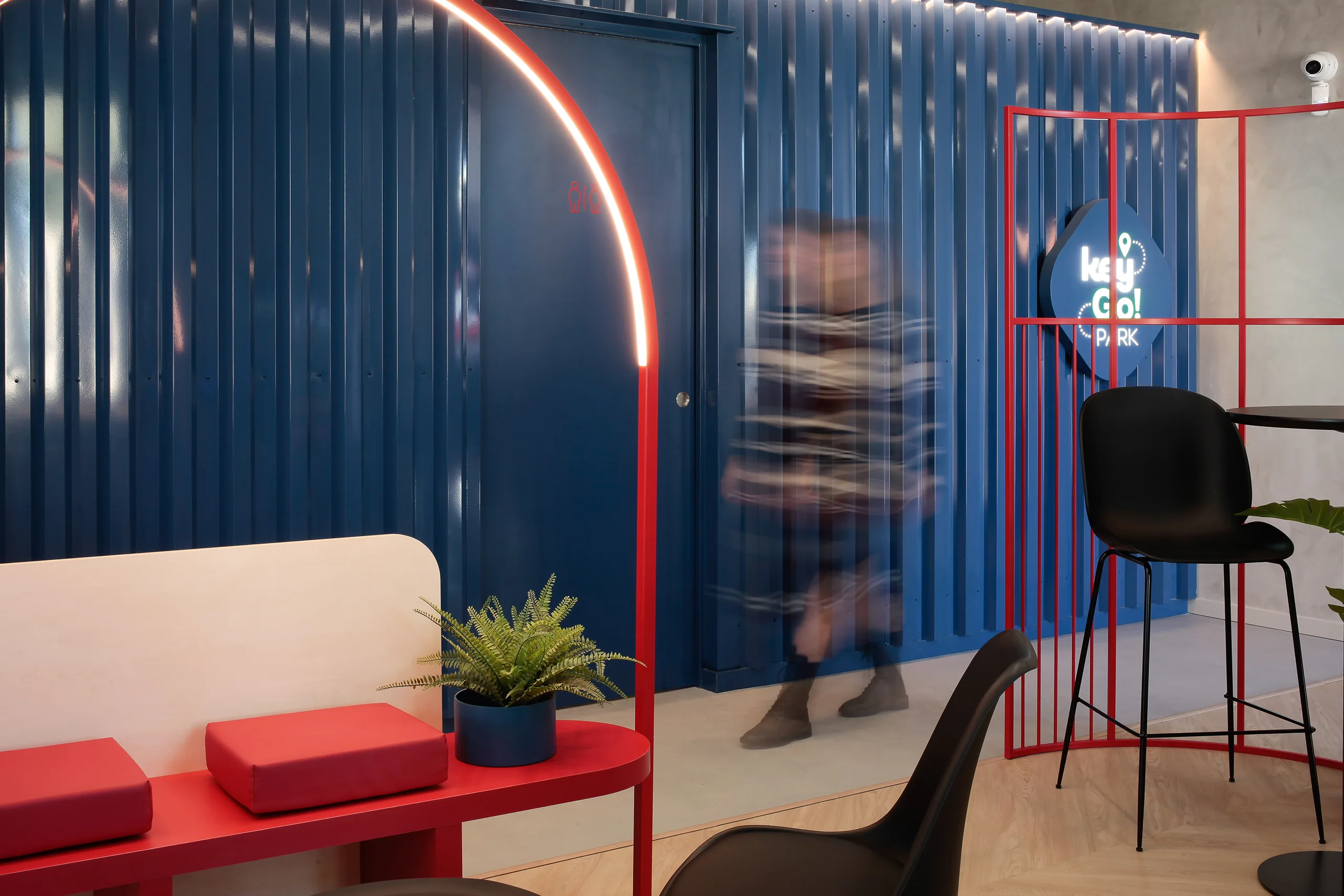 Mostradores rojos numerados de Key Go Rent! en Alicante con rótulo retroiluminado y panel azul petróleo bajo cubierta de cerchas